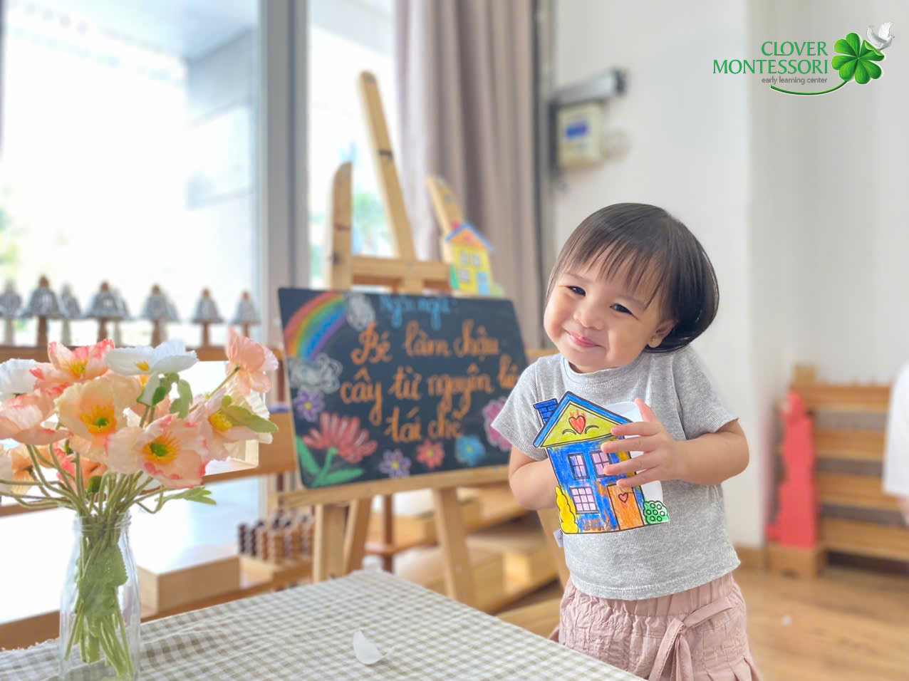 Bé mỉm cười khoe bức tranh ngôi nhà tự tay tô màu
