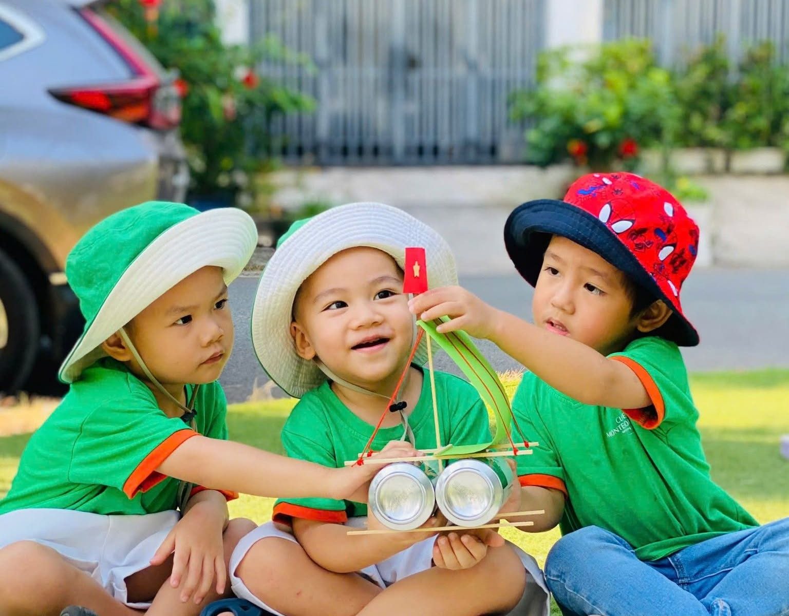 Các bé ngồi chơi cùng nhau ngoài sân trường
