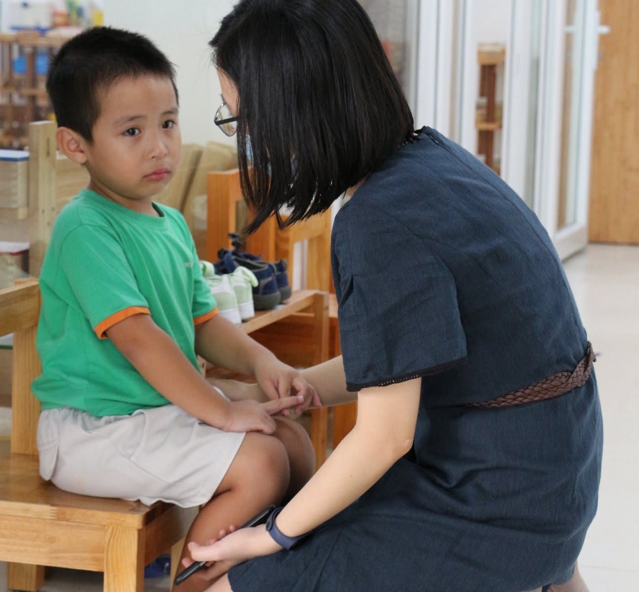 Cô giáo Clover Montessori ngồi xuống ngang tầm mắt, trò chuyện dịu dàng với một bé trai