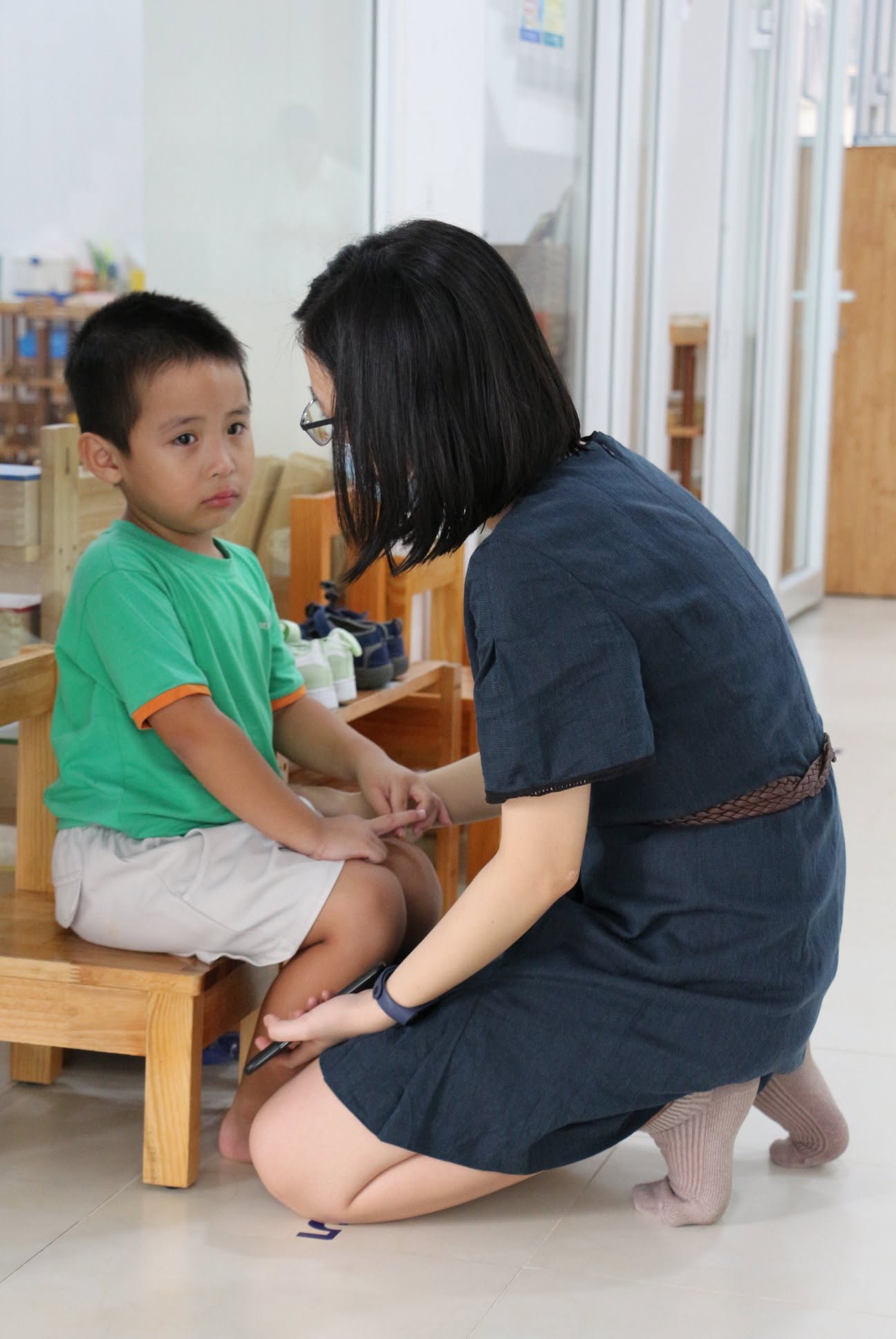 Cô giáo Clover Montessori ngồi xuống ngang tầm mắt, trò chuyện dịu dàng với một bé trai