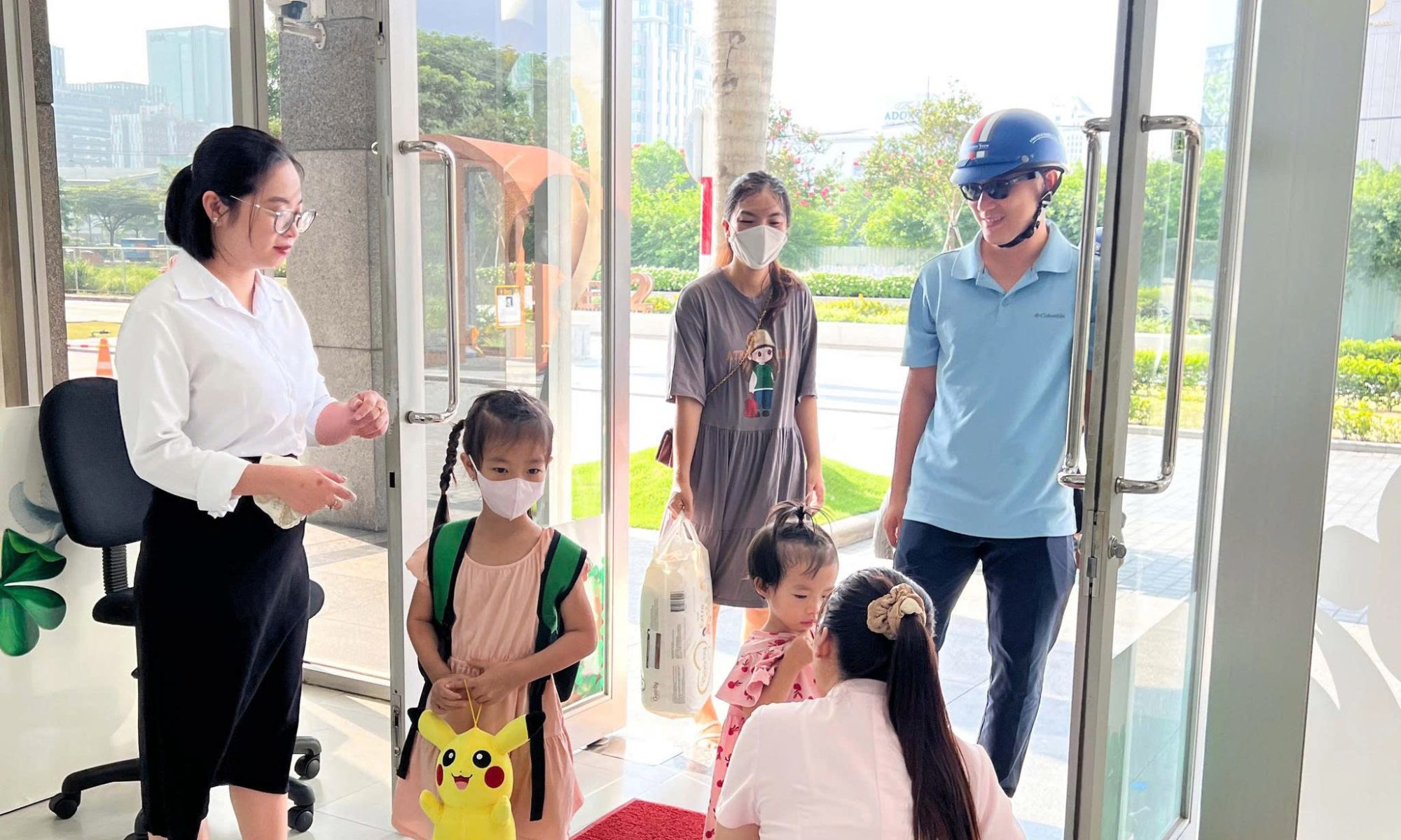 Cô giáo đón bé và phụ huynh ở cửa trường buổi sáng