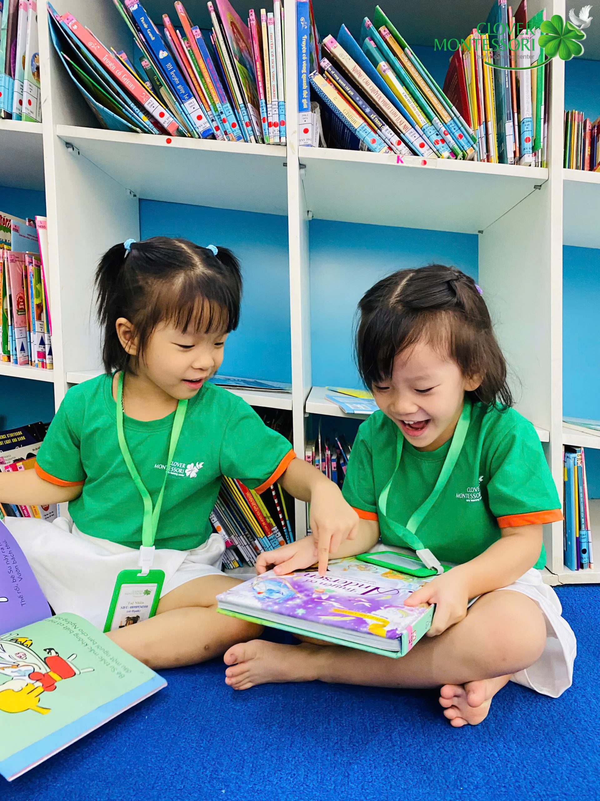 Hai bé cùng đọc sách và cười vui bên nhau