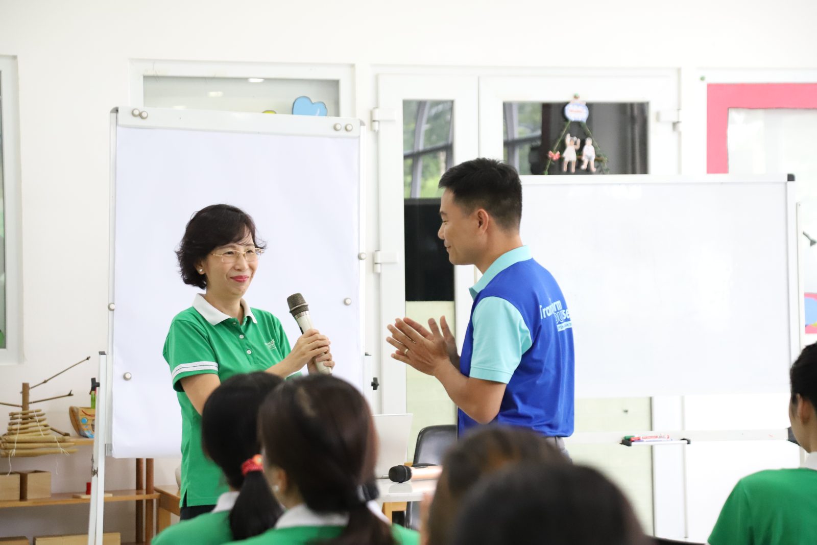 Bà giáo Trúc cầm micro trao đổi với một người trong buổi đào tạo, phía sau là bảng trắng