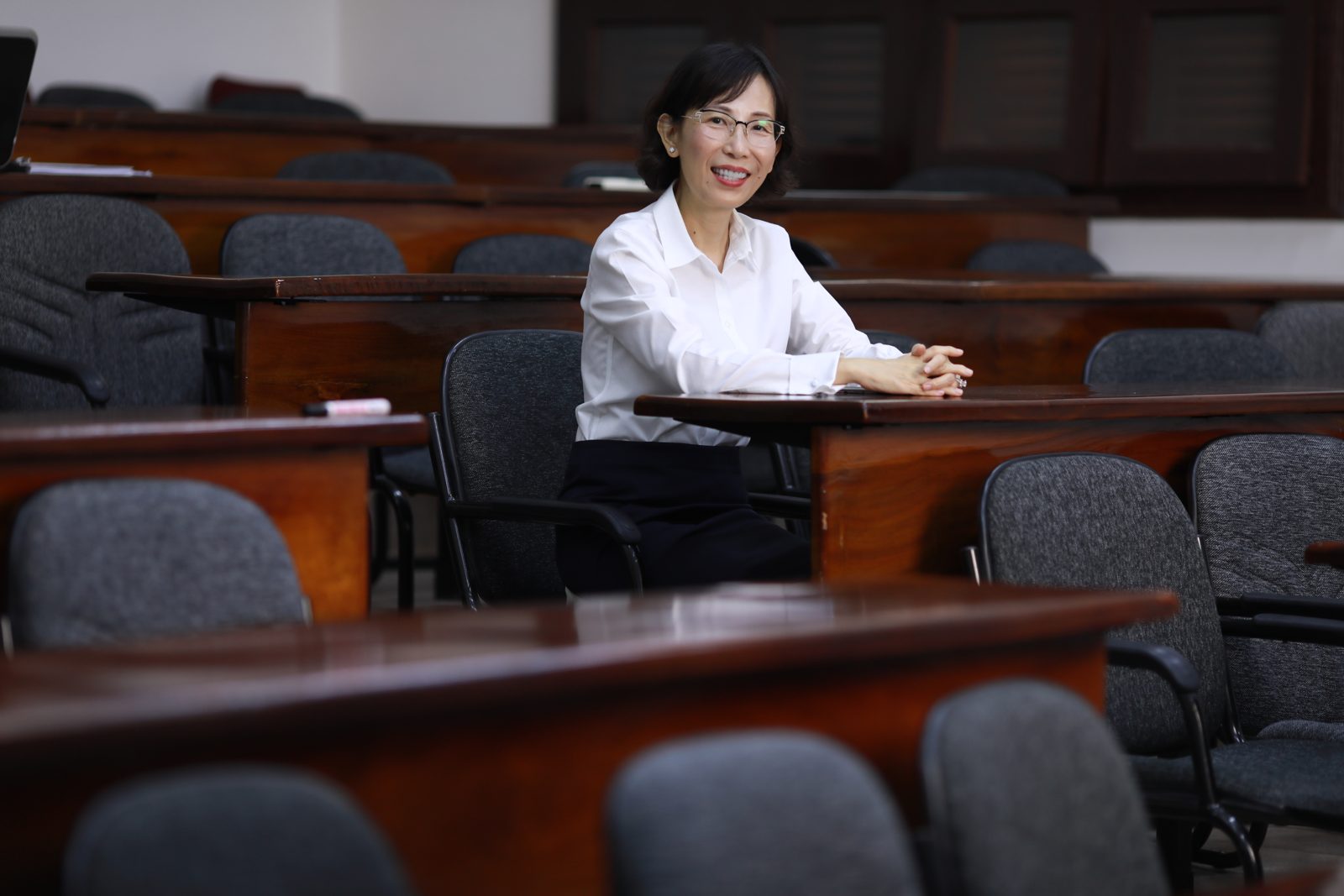 Bà giáo Trúc ngồi mỉm cười giữa những dãy bàn trong một giảng đường