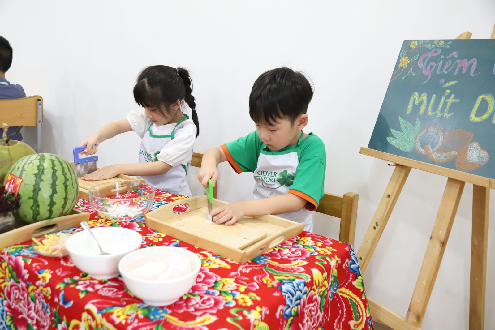 Hai bé tự cắt trái cây trong hoạt động thực hành cuộc sống