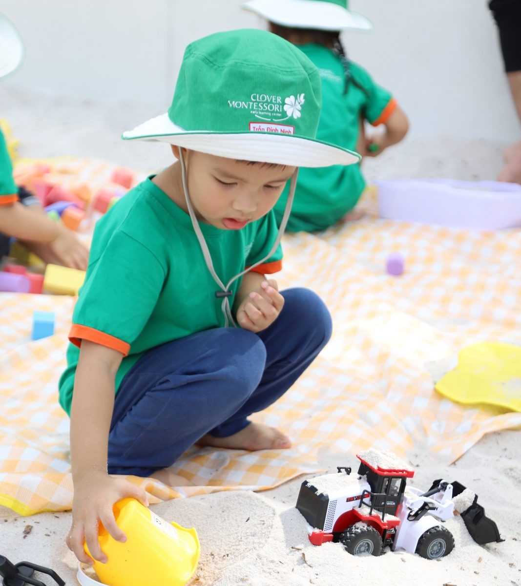 Bé ngồi tập trung chơi cát, mải mê với chi tiết nhỏ