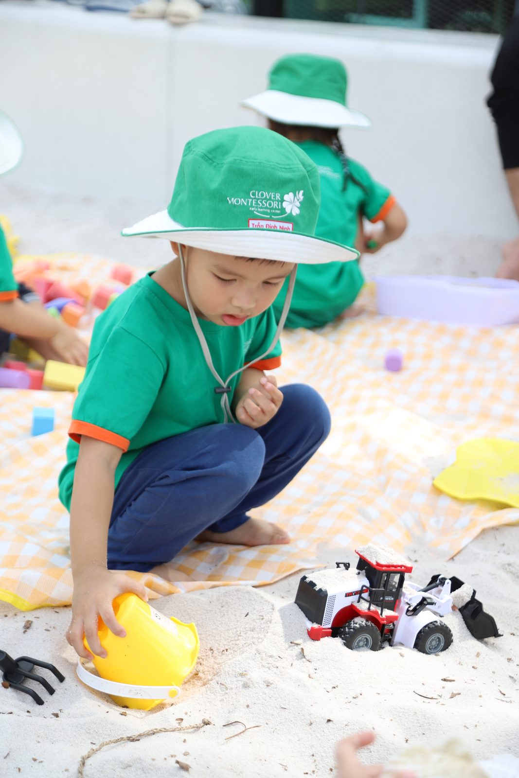Bé ngồi tập trung chơi cát, mải mê với chi tiết nhỏ
